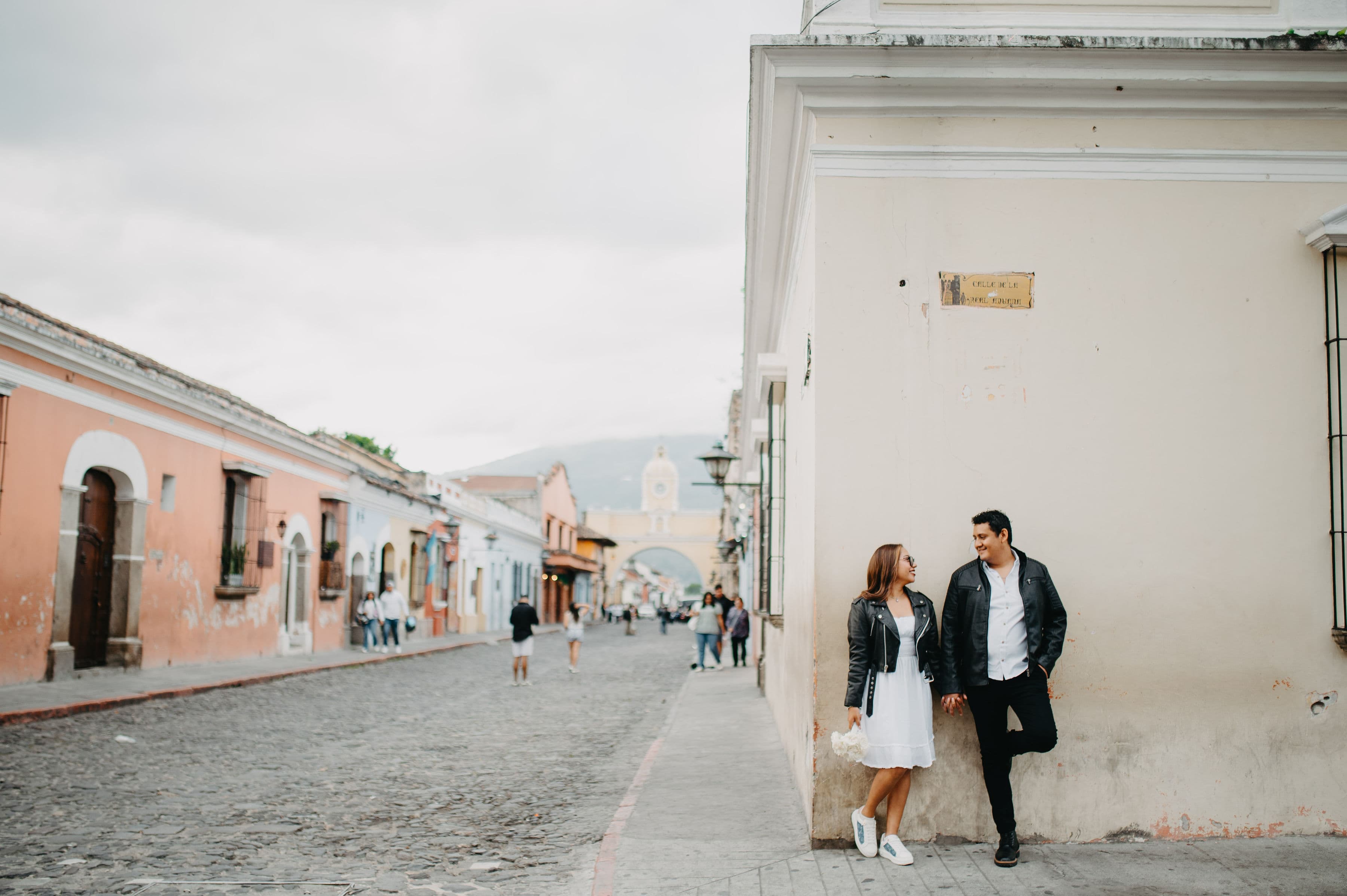 Sergio y Sálery tomados de la mano en una calle empedrada de Antigua, con el Arco de Santa Catalina al fondo